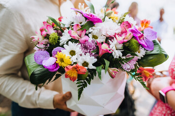A man at a holiday, birthday, wedding holds in his hands a beautiful wedding bouquet of multi-colored flowers in a paper basket. Photography, portrait.