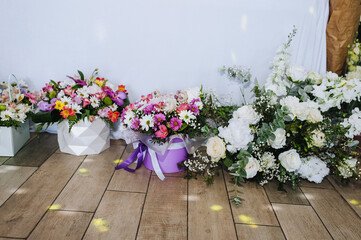 Beautiful bouquets of flowers in paper wrapped baskets stand indoors. Wedding photography, birthday present.