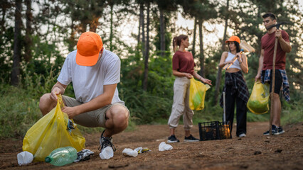 teenage friends young men women pick up waste garbage to clean forest
