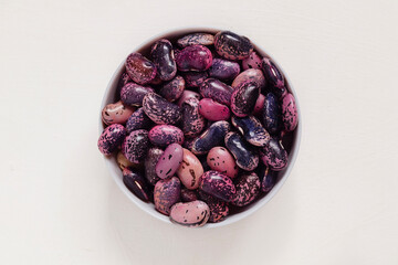 Round bowl with bright colorful scarlet runner beans on a white background. Top view. Copy space.