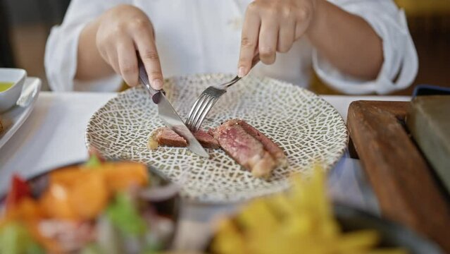 Young beautiful hispanic woman eating meat from steak at the restaurant