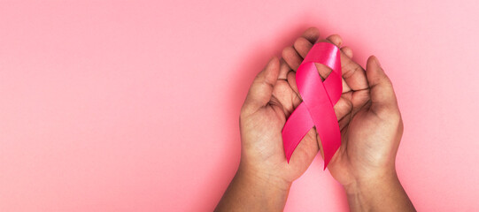 pink ribbon placed on the hand of an obese woman suffering from cancer, world cancer day, healthcare and medicine backdrop, suicide prevention, children health care.
