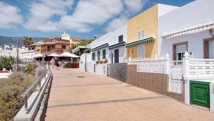 Papier Peint photo autocollant les îles Canaries Boardwalk along the seafront lined with traditional homes now converted into fish and seafood restaurants visited by tourists and locals alike in La Caleta, Tenerife, Canary Islands, Spain