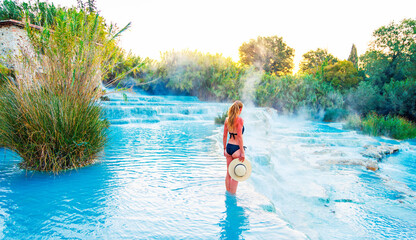 Young female tourist enjoying Natural spa with waterfalls at Saturnia thermal baths- Tuscany in...