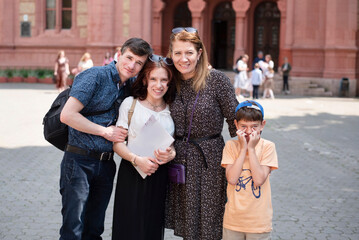 Dad, mom and younger brother congratulate their daughter on graduating from music school, girl studied piano for a long time and is now a young musician. The girl has a diploma in her hands