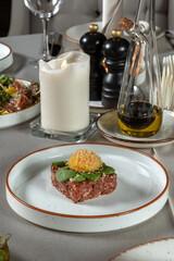 Fresh beef tartar dish with tasty vegetables. Garnished with lettuce leaves. Vertical photo