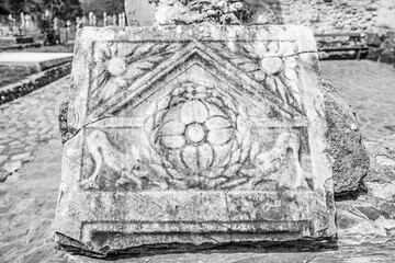 Ancient roman ruin at Densuș church yard, Hunedoara county, Transylvania, Romania; antique roman carved stone plaque in black and white