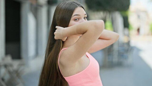 Young beautiful girl smiling confident combing hair at street