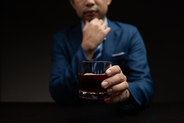 Man with glass of whiskey, businessman drinking whiskey in dark room, drinking alcohol drunk, businessman stress. Intoxicated drink concept.