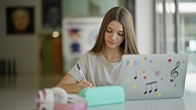 Young beautiful girl student using laptop breaking paper looking upset at library