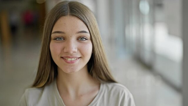 Young beautiful girl smiling confident sitting on table at library