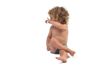  view of a boy in underpants sitting on the floor turning and pointing  on white background (3 year old)