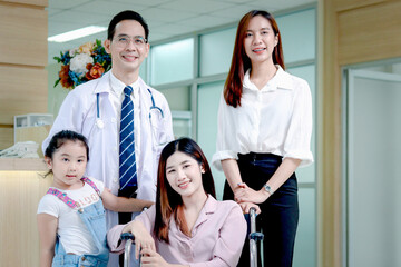 Obraz premium Female Asian patient in wheelchair with family come to hospital, be taken care by senior male doctor at medical clinic, happy patient feels better after treatment, medical consulting with professional