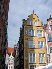 Fototapeta na wymiar Yellow Gdańsk townhouse with St. Mary's Church visible in the background