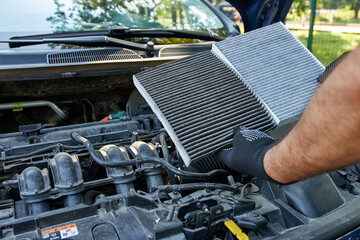 The old clogged air filter is replaced with a new one. Car repair and maintenance.