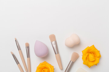 Makeup brushes and sponges on color background, top view