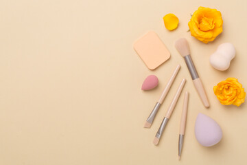 Makeup brushes and sponges on color background, top view