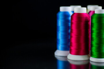 set of different color sewing threads,on black background.