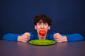 A young funny guy eats an apple. Vegetarianism and a healthy lifestyle.