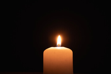 A memorial candle on a dark background. Burning candle on black background, copy space