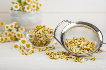 Dry chamomile flowers on a wooden table. Soothing chamomile tea. Herbal drink. flat layout. Space for text.Copy space.Medical prevention and immune concept. Folk alternative medicine.