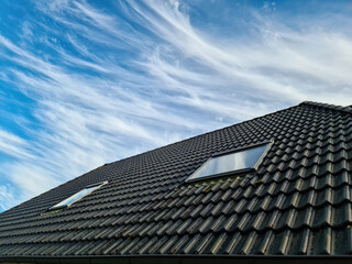 Fototapeta na wymiar Open roof window in velux style with black roof tiles.