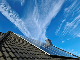 Solar panels producing clean energy on a roof of a residential house - obrazy, fototapety, plakaty