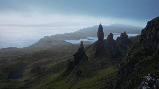 Atmospheric view of high sharp cliffs towering over the lakes and sea, and the looming rain cloud at sunrise. Video with the panning camera motion. The Old Man of Storr, The Isle of Skye, Scotland, UK