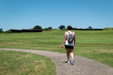 Mulher a caminhar numa pequena estrada a meio um campo de golfe num dia ensolarado