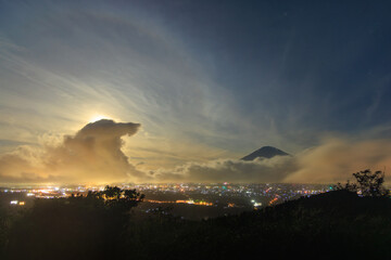 Obraz premium Giant cloud wave approaches Mt. Fuji on night of full moon