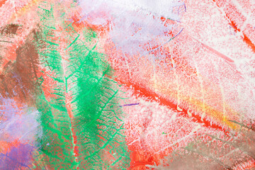 White , purple and green acrylic paint imprint with leaves pattern  on red background paper