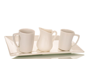 Two ceramic cups and one milk jug on a white ceramic tray, macro, isolated on white background.