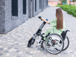 A woman in a wheelchair with an assistive device for manual control. Electric handbike. 