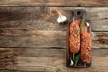 raw Lula kebab on skewers with spices on a cutting board. banner, menu, recipe place for text, top view