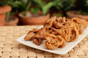 Moroccan chebakias on a white plate in a patio with plants