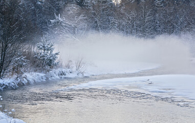 Cold winter river, steam visible above water, dark trees on side