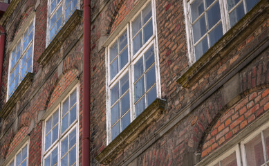 Old wooden windows on the facade of an old brick building with a water pipe