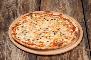 Studio shot of a hand made mushroom pizza on beautiful weathered wooden table