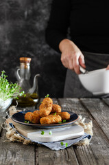 
Plato de croquetas caseras con presencia de cocinera. Ambiente rústico y natural.