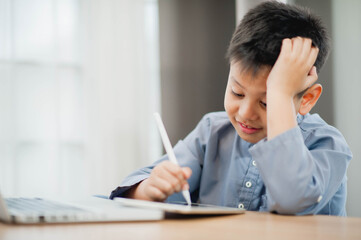 Little Asian boy student using computer laptop and tablet learning. Educational concept Social distancing, staying at home, presenting a modern educational way of life.