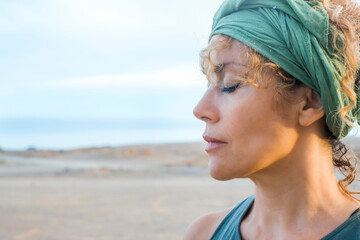 ONe middle age pretty woman outdoor with closed eyes and serene expression and nature outdoor beach...