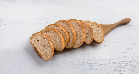 Wooden board with sliced bran bread on light blue textured background