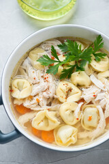Soup with italian tortellini, torn chicken fillet and carrot, vertical shot, closeup, selective focus