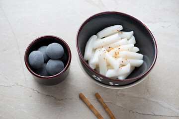 Tteokbokki and mochi or korean traditional street food and snack, horizontal shot on a beige stone background, selective focus