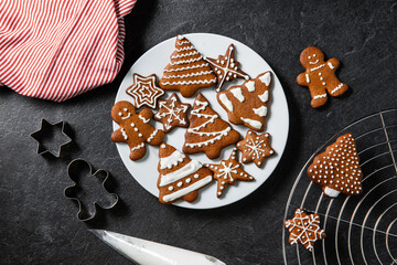 christmas baking, cooking and food concept - close up of iced gingerbread cookies on plate, molds,...