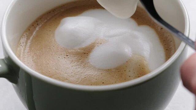 Adding milk foam to coffee cup for fresh cappuccino preparation. Espresso with latte morning hot drink with aroma macro view