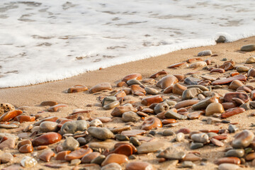 Fototapeta na wymiar Sea surf and wet pebbles on sand beach coast, close-up, selective focus