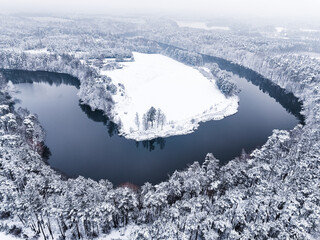 Fototapeta na wymiar Flying above river in snow-covered forest in winter, Poland.