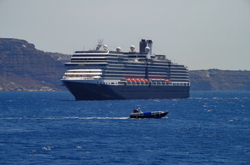 Luxury cruiseship cruise ship liner Eurodam anchoring at sea on sunny summer day during Mediterranean Greek Island cruise with shore and rocky island in background
