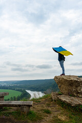 Man with Ukrainian flag on Dniester River canyon. Landscape with canyon, forest and a river in front. Dniester River, Ukraine